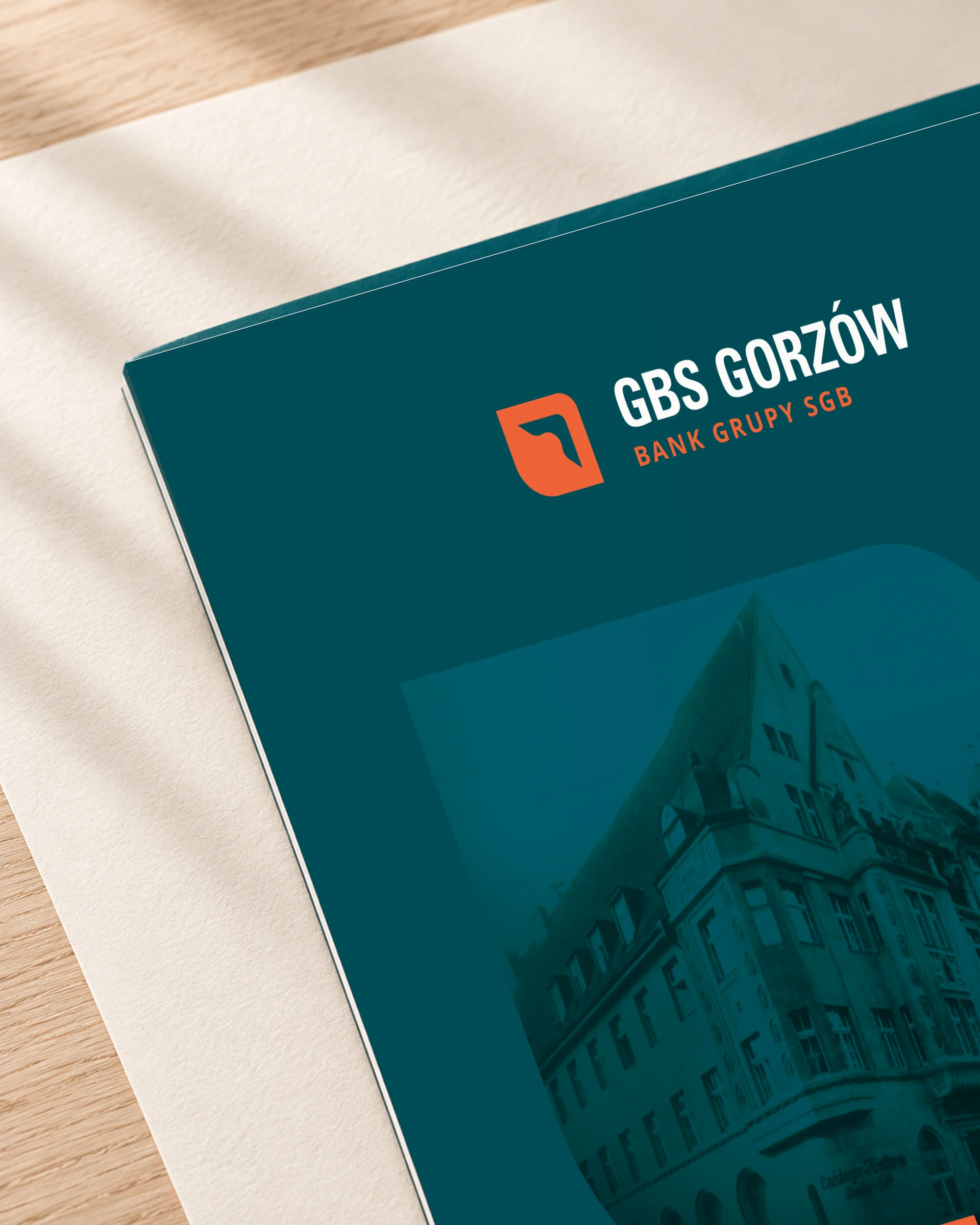 Róg okładki teczki GBS Gorzów z logo i fragmentem motywu z historyczną siedzibą