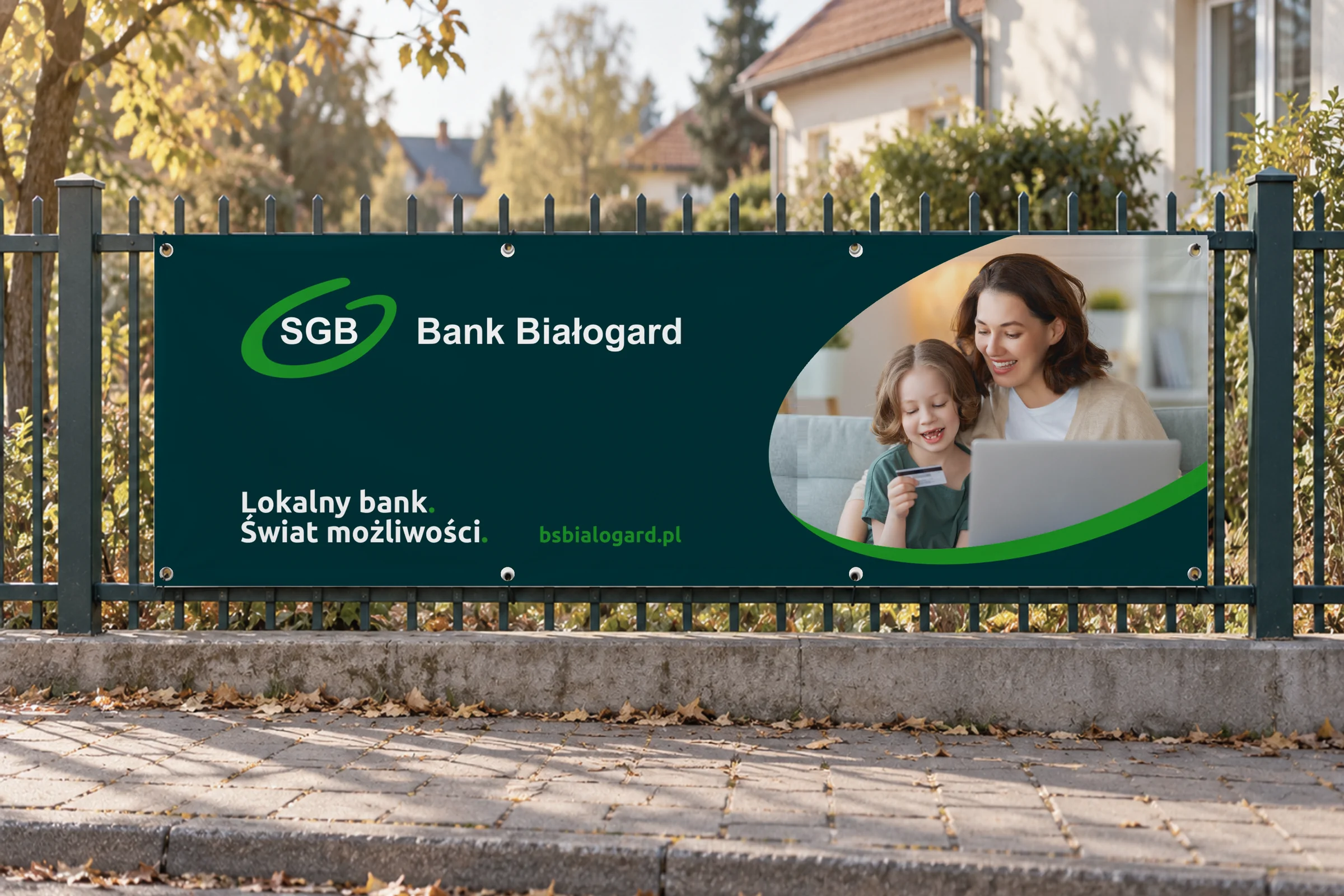 Baner z hasłem „Lokalny bank. Świat możliwości.” na ogrodzeniu przy ulicy